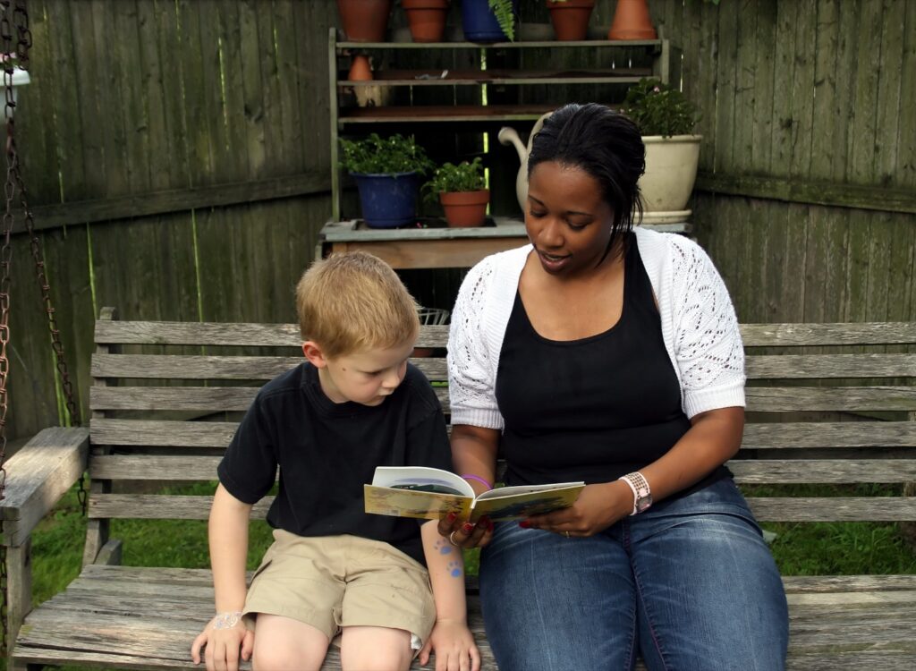 A carer reading a book with a young boy